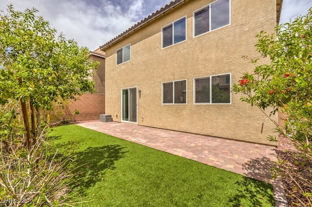 rear view of house with a tile roof, a patio area, a yard, stucco siding, and fence
