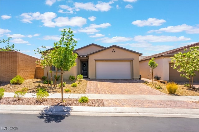 ranch-style home with stucco siding, decorative driveway, and a garage