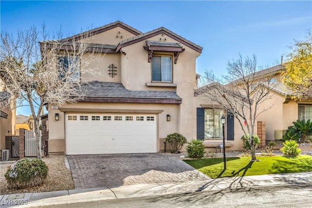 view of front of home with stucco siding, decorative driveway, a gate, and an attached garage