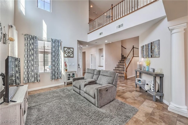 living room with visible vents, decorative columns, a high ceiling, and baseboards