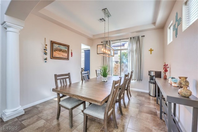 dining area with stone finish floor, a raised ceiling, visible vents, an inviting chandelier, and decorative columns