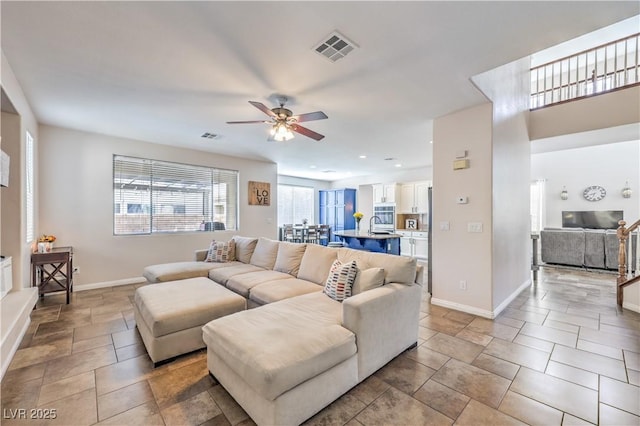 living area featuring baseboards, visible vents, and a ceiling fan