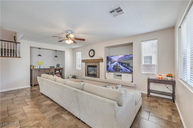 living room with visible vents, ceiling fan, a wealth of natural light, and a glass covered fireplace