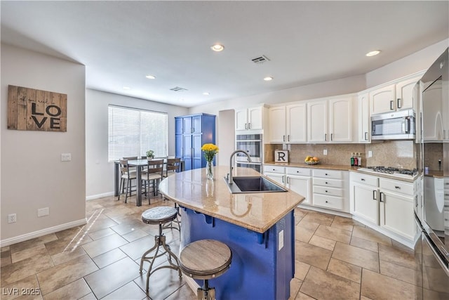 kitchen featuring a kitchen breakfast bar, white cabinets, a sink, stainless steel appliances, and baseboards