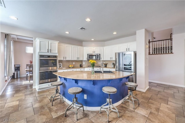 kitchen with light stone countertops, appliances with stainless steel finishes, white cabinets, backsplash, and baseboards