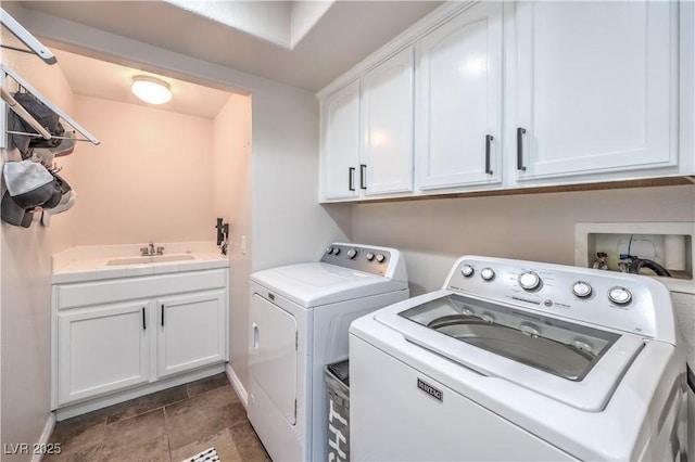laundry room with stone finish floor, washing machine and clothes dryer, a sink, baseboards, and cabinet space