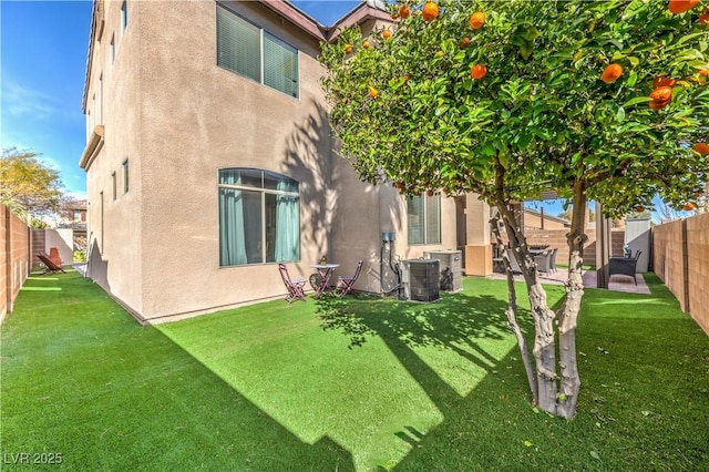 back of house featuring central air condition unit, a fenced backyard, stucco siding, and a lawn