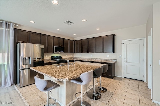 4902 Guysborough St, Las Vegas, NV 89148 - kitchen featuring stainless steel appliances, a sink, dark brown cabinetry, a breakfast bar, and light stone counters