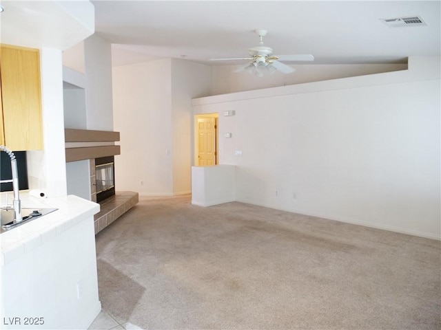 6508 Alpine Forest Ct, Las Vegas, NV 89149 - unfurnished living room with a ceiling fan, light colored carpet, vaulted ceiling, a fireplace, and baseboards