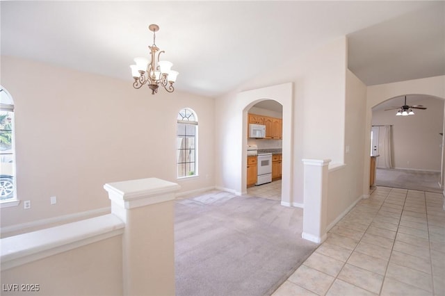 interior space with light tile patterned floors, arched walkways, vaulted ceiling, light carpet, and ceiling fan with notable chandelier