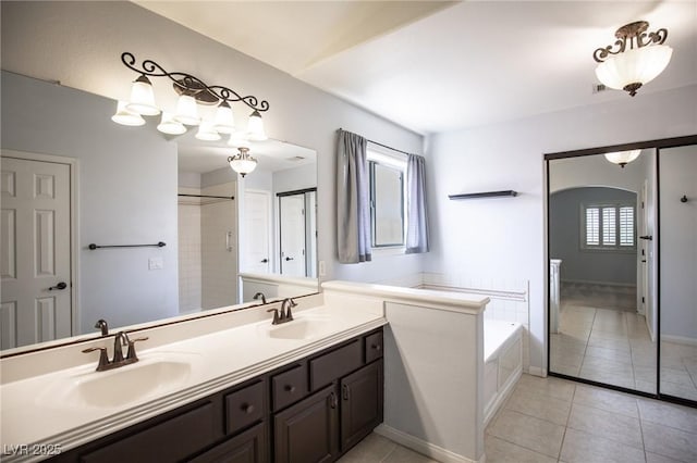 full bath featuring double vanity, a bath, tile patterned flooring, and a sink