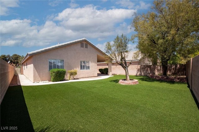 rear view of property with a yard, stucco siding, and a fenced backyard