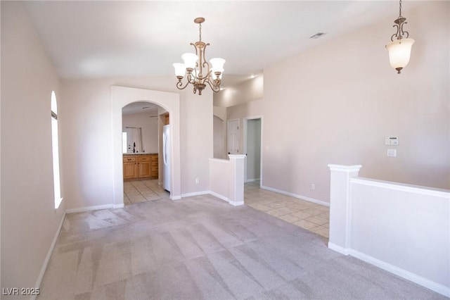 unfurnished dining area featuring a notable chandelier, visible vents, baseboards, arched walkways, and light colored carpet