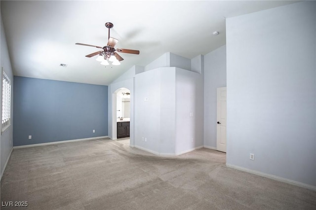 interior space with ceiling fan, visible vents, vaulted ceiling, light carpet, and arched walkways