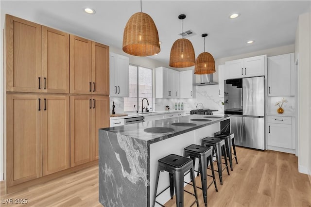10613 Turquoise Valley Dr, Las Vegas, NV 89144 - kitchen featuring light wood-style flooring, a breakfast bar, dark stone counters, stainless steel appliances, and wall chimney range hood