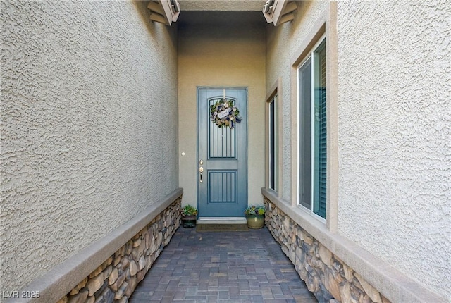 view of exterior entry with stucco siding and stone siding
