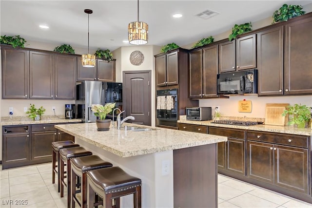 kitchen featuring black appliances, light tile patterned flooring, visible vents, and dark brown cabinetry