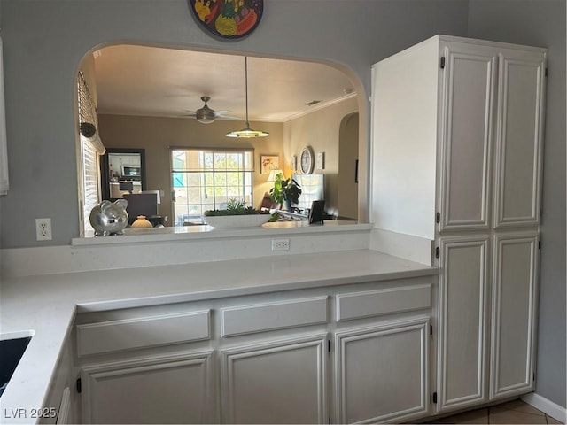 kitchen featuring ceiling fan, light countertops, and arched walkways