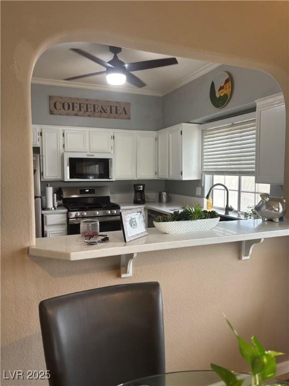 kitchen featuring stainless steel appliances, ceiling fan, a peninsula, ornamental molding, and arched walkways