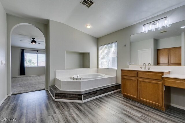 1048 Painted Daisy Ave, Henderson, NV 89074 - full bathroom featuring a garden tub, vanity, wood finished floors, a ceiling fan, and vaulted ceiling