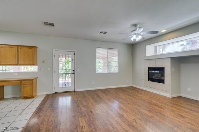 1048 Painted Daisy Ave, Henderson, NV 89074 - unfurnished living room featuring light wood-style flooring, a tiled fireplace, and a ceiling fan