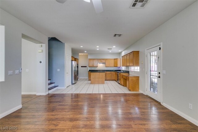 1048 Painted Daisy Ave, Henderson, NV 89074 - kitchen with stainless steel refrigerator with ice dispenser, light wood-style floors, ceiling fan, a center island, and dark countertops