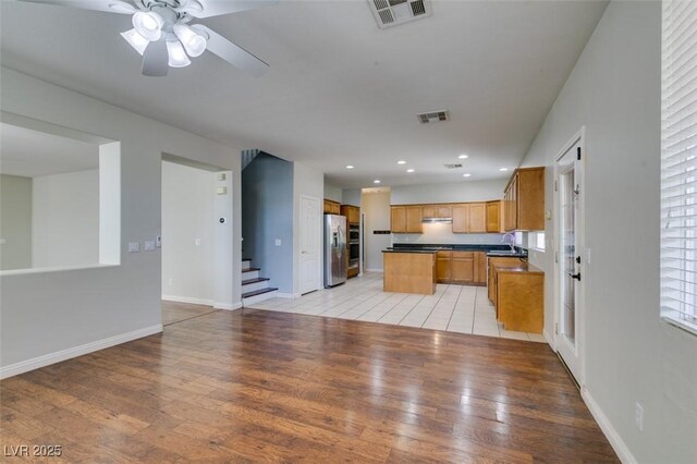 1048 Painted Daisy Ave, Henderson, NV 89074 - kitchen featuring stainless steel fridge with ice dispenser, light wood-style floors, recessed lighting, dark countertops, and a center island