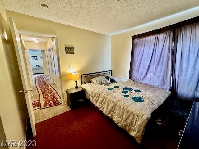 bedroom featuring a textured ceiling and dark colored carpet