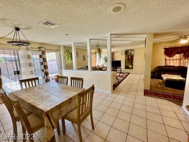 dining space with light tile patterned flooring, visible vents, and a textured ceiling