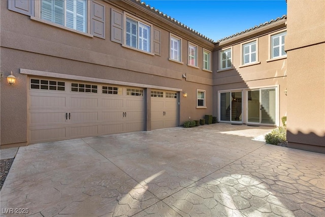 2717 Mona Lisa St, Henderson, NV 89044 - back of house featuring stucco siding, a garage, driveway, and a tiled roof