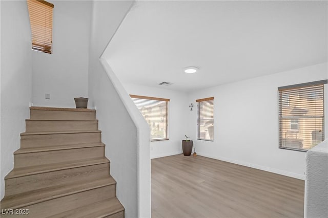 stairway with visible vents, wood finished floors, and baseboards