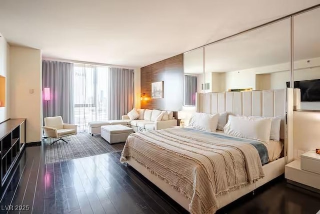 bedroom featuring expansive windows and dark wood-type flooring