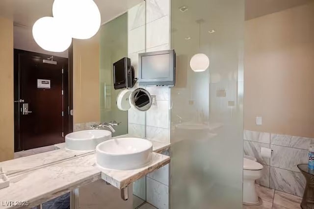 full bath featuring toilet, tile walls, a sink, and tile patterned floors