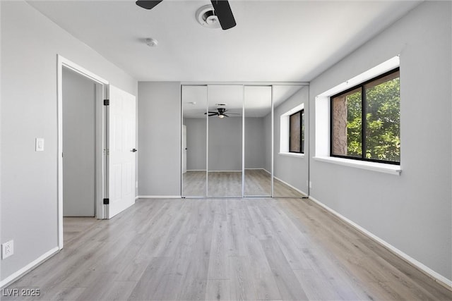 unfurnished bedroom featuring wood finished floors, a closet, a ceiling fan, and baseboards