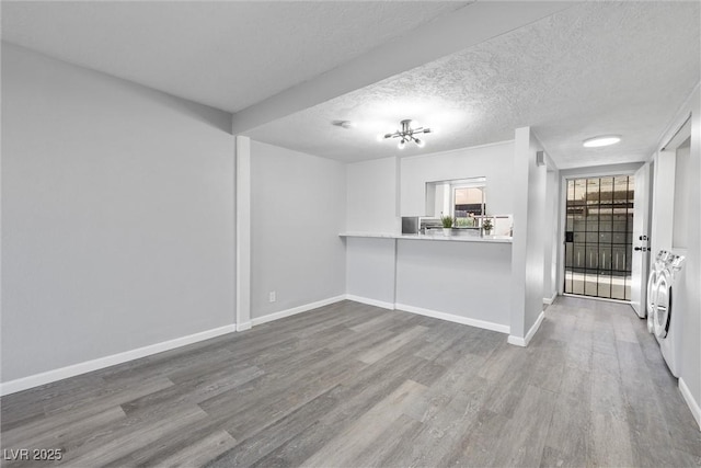 unfurnished living room with baseboards, wood finished floors, and washer and clothes dryer