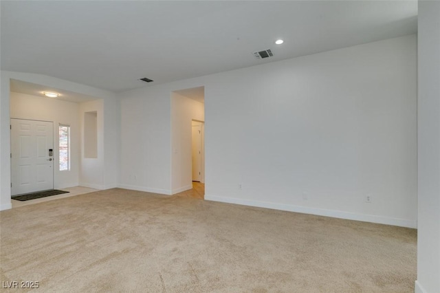 spare room with baseboards, visible vents, and light carpet