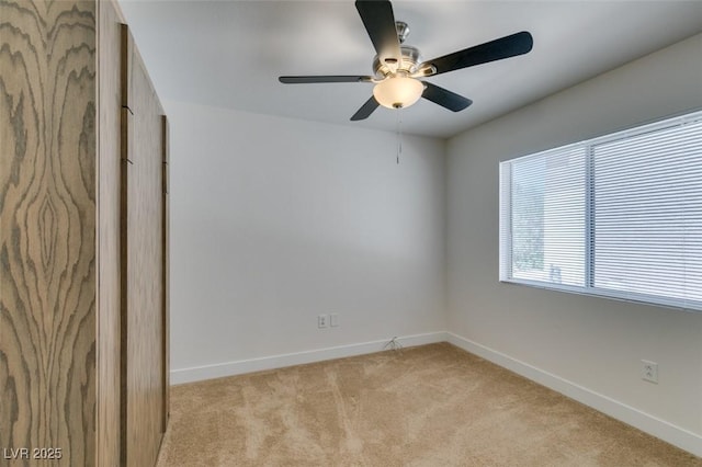 unfurnished room featuring a ceiling fan, light colored carpet, and baseboards