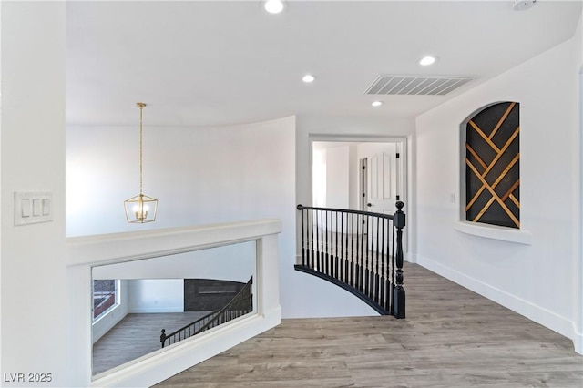 hallway with recessed lighting, an upstairs landing, visible vents, baseboards, and wood finished floors