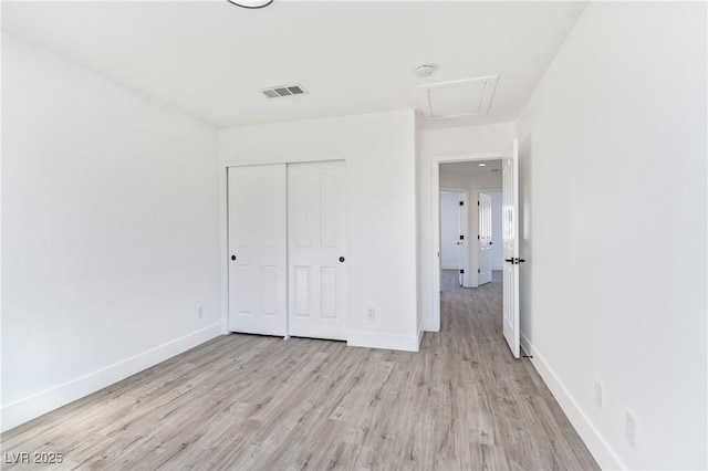 unfurnished bedroom with visible vents, a closet, light wood finished floors, and baseboards