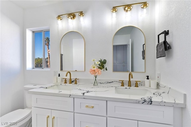 bathroom featuring double vanity, toilet, and a sink