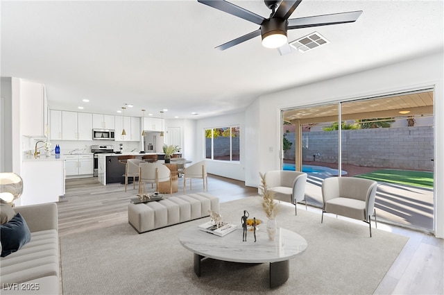 living area with visible vents, a ceiling fan, light wood-style flooring, and recessed lighting
