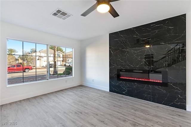 interior space featuring visible vents, wood finished floors, a ceiling fan, and a premium fireplace