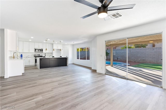 unfurnished living room with recessed lighting, light wood-style floors, ceiling fan, a sink, and visible vents
