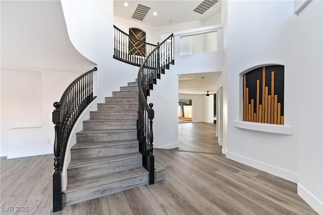 staircase featuring baseboards, visible vents, and wood finished floors