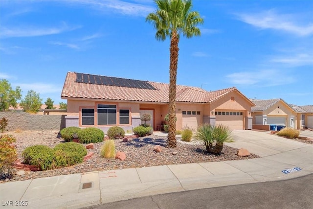 view of front of home featuring stucco siding, roof mounted solar panels, an attached garage, driveway, and a tile roof