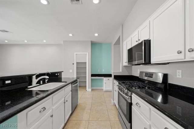kitchen with visible vents, dark stone counters, white cabinetry, a sink, and appliances with stainless steel finishes