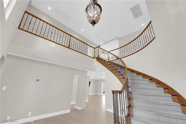 2595 Aviv Ct, Las Vegas, NV 89121 - stairs with visible vents, baseboards, an inviting chandelier, arched walkways, and a high ceiling