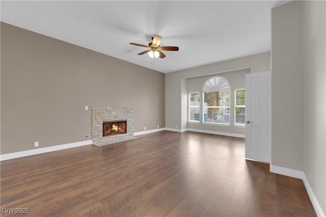 2595 Aviv Ct, Las Vegas, NV 89121 - unfurnished living room featuring baseboards, a ceiling fan, a stone fireplace, and dark wood-style flooring