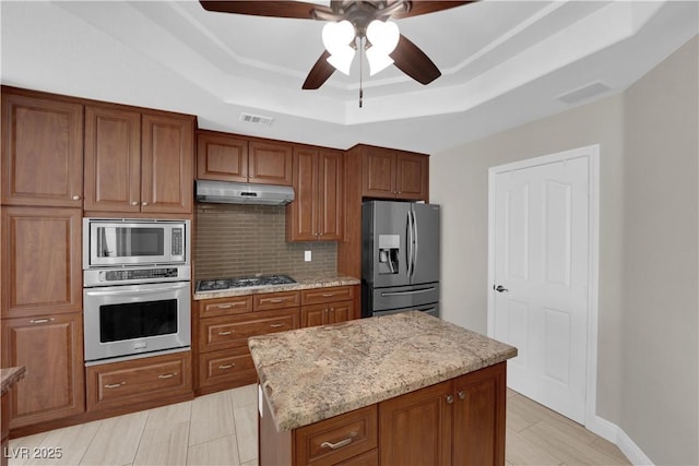 2595 Aviv Ct, Las Vegas, NV 89121 - kitchen with decorative backsplash, stainless steel appliances, under cabinet range hood, ceiling fan, and a tray ceiling