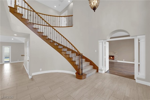 2595 Aviv Ct, Las Vegas, NV 89121 - staircase featuring baseboards, high vaulted ceiling, a warm lit fireplace, and recessed lighting